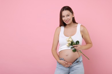 Photo of Beautiful pregnant woman with roses on pink background, space for text