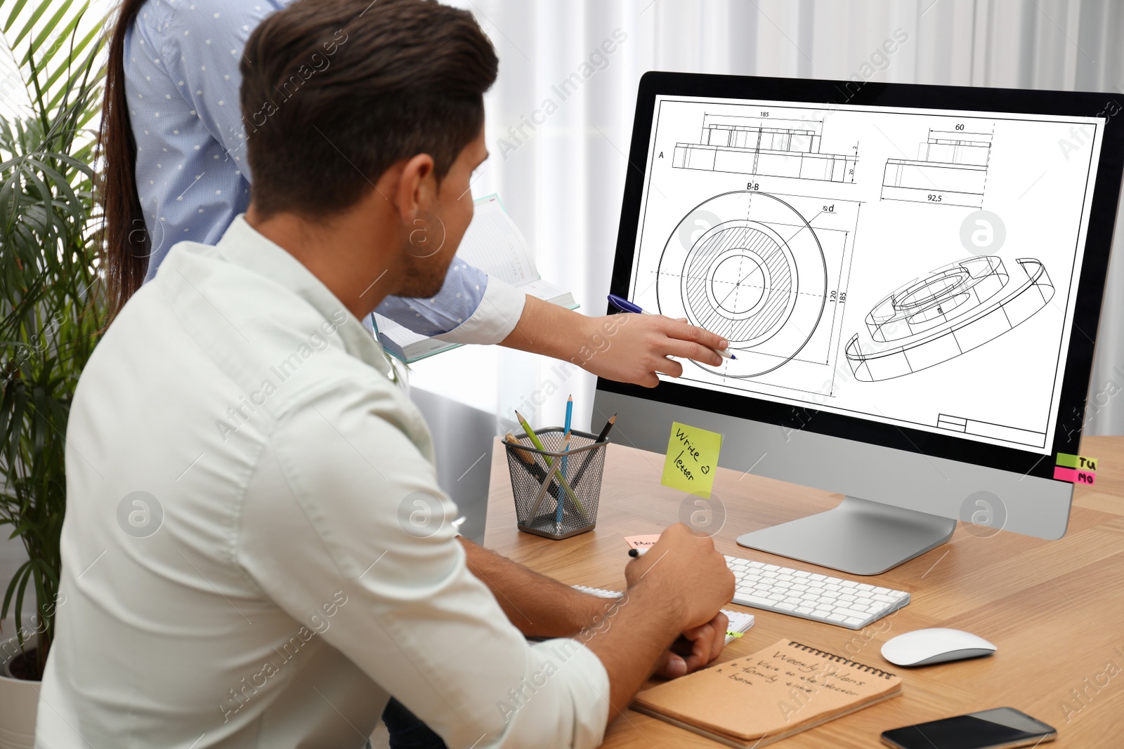 Image of Colleagues working with technical drawing on computer in office