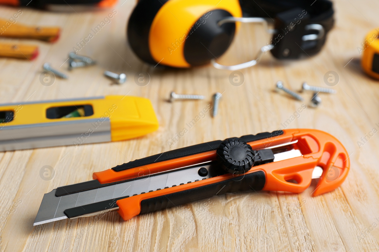 Photo of Utility knife and different tools on wooden table, closeup