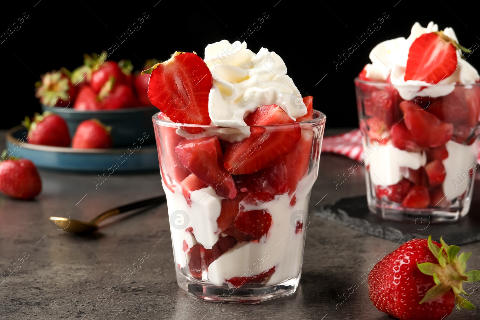 Photo of Delicious strawberries with whipped cream served on grey table