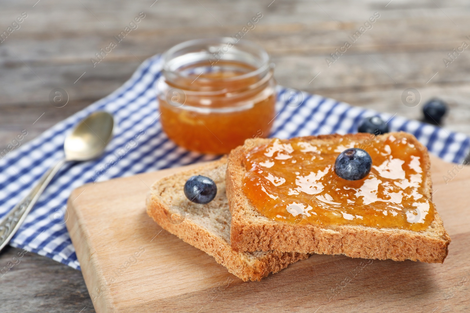 Photo of Toasts with sweet jam on wooden board, closeup