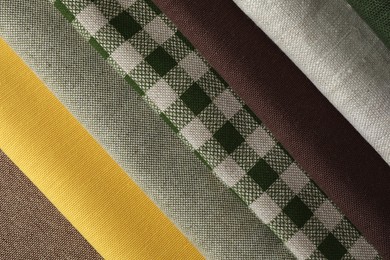 Photo of Many different fabrics on brown cloth, closeup