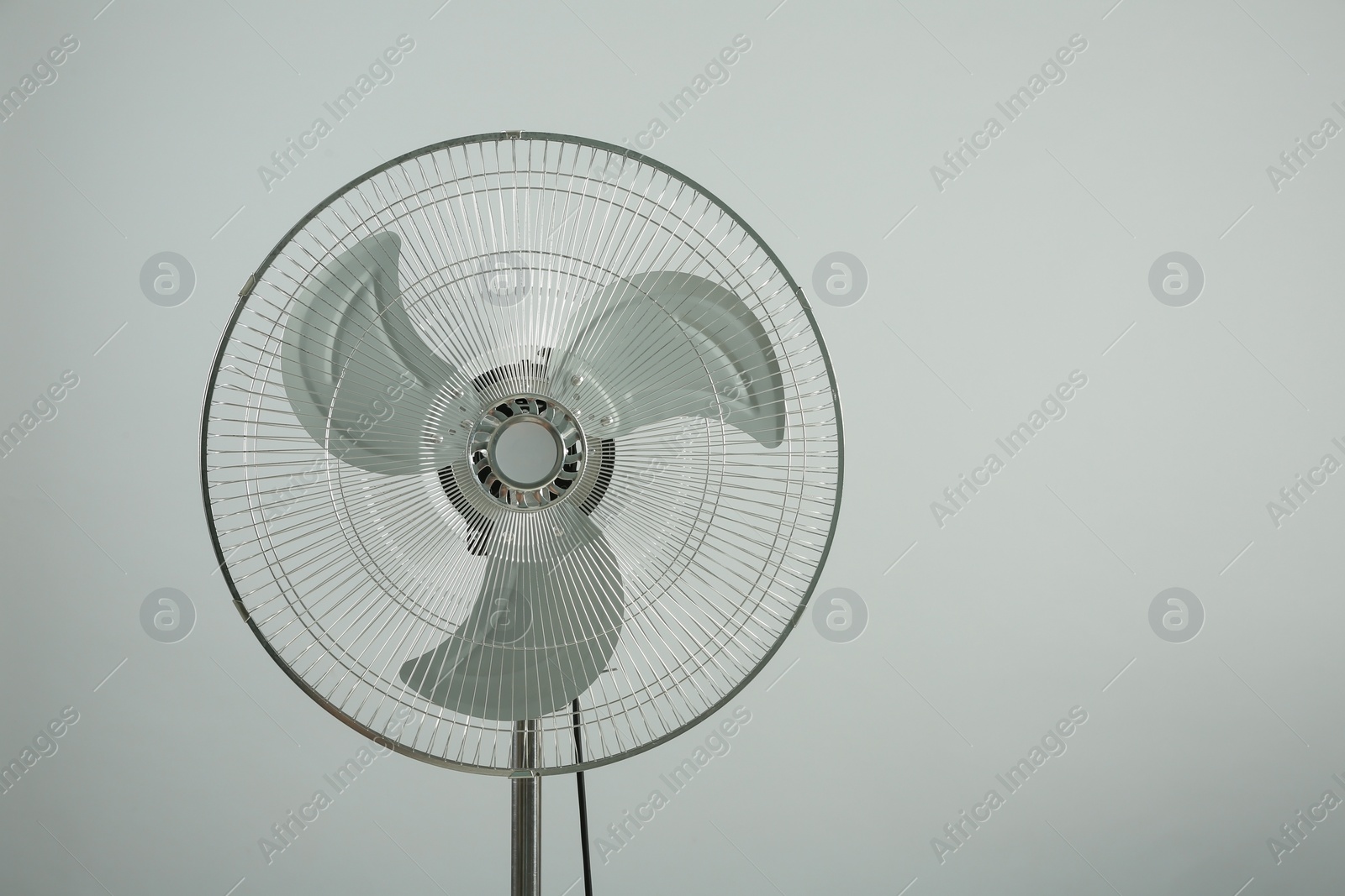 Photo of Electric fan on light grey background, space for text. Summer heat