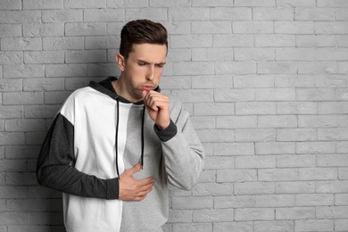 Photo of Young man coughing on brick wall background