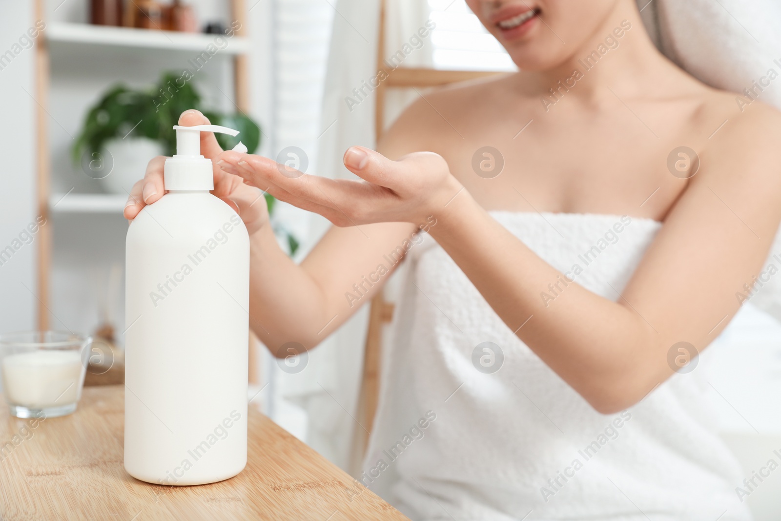 Photo of Young woman applying body cream on hands in bathroom, closeup