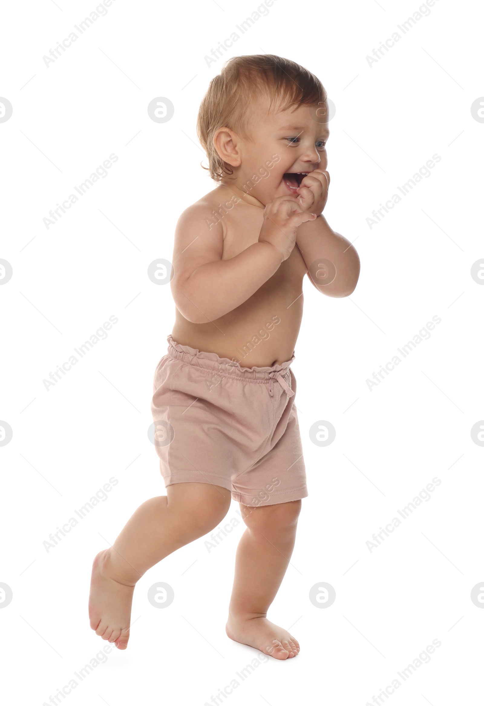 Photo of Cute baby in shorts learning to walk on white background