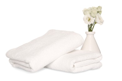 Photo of Folded soft terry towels with beautiful flowers on white background
