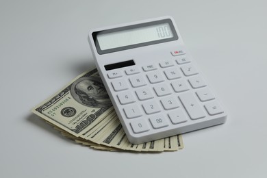 Photo of Money exchange. Dollar banknotes and calculator on white background, closeup