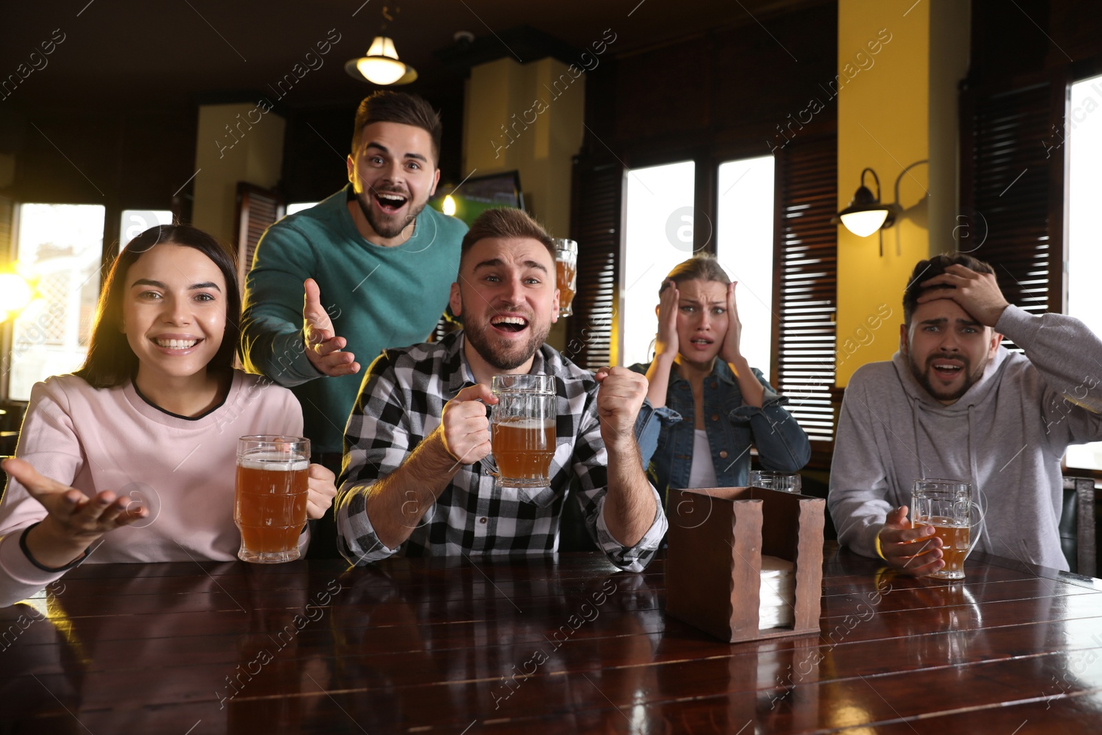 Photo of Group of friends watching football in sport bar