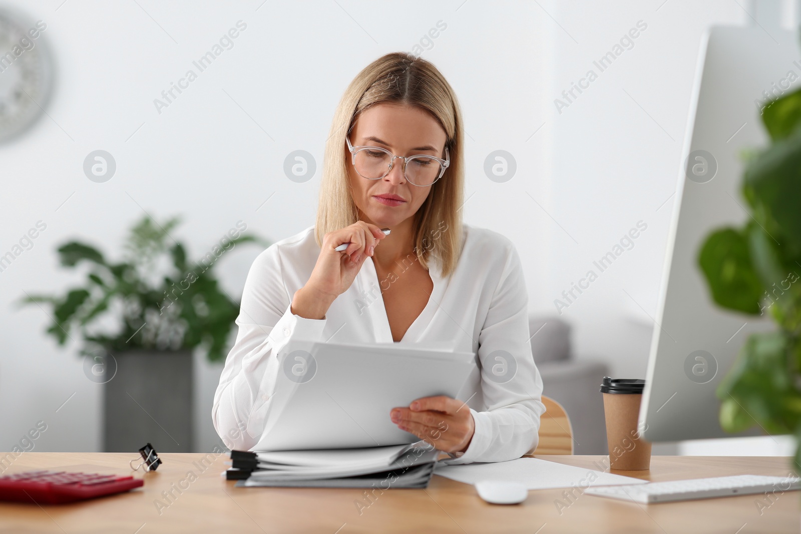 Photo of Woman working with documents at wooden table in office