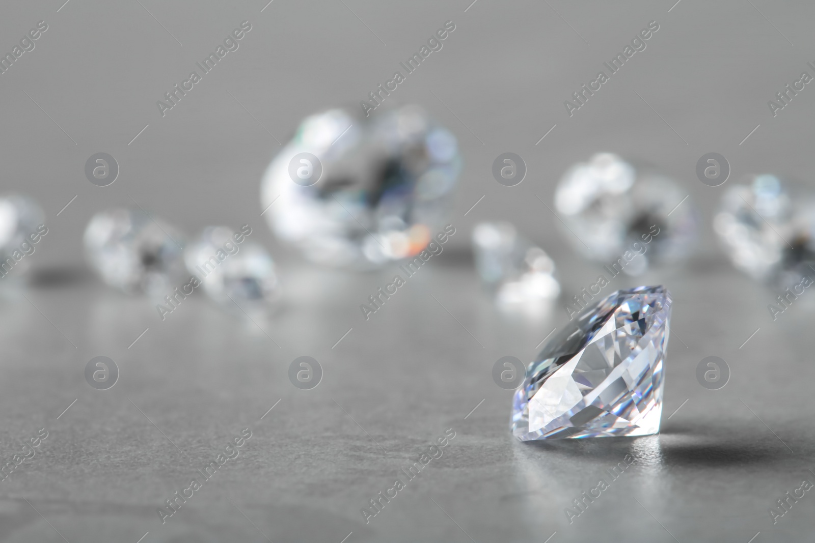 Photo of Beautiful shiny diamond on gray table, space for text