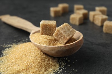 Photo of Spoon with brown sugar cubes on grey table, closeup