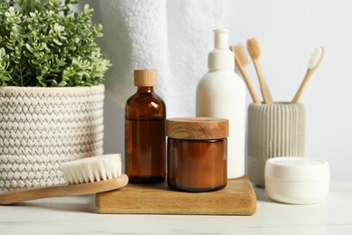 Different bath accessories and personal care products on light marble table against white wall