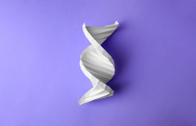 Photo of Paper model of DNA molecular chain on violet background, top view