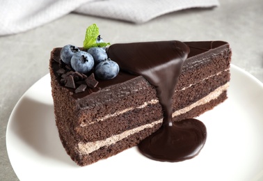 Photo of Delicious fresh chocolate cake with blueberries on light table, closeup