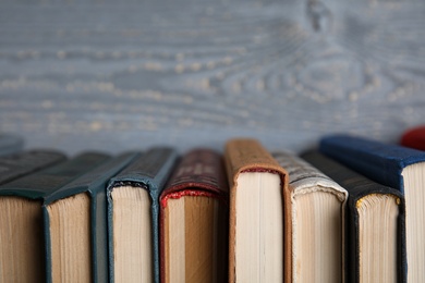 Photo of Stack of hardcover books on grey wooden background, closeup. Space for text