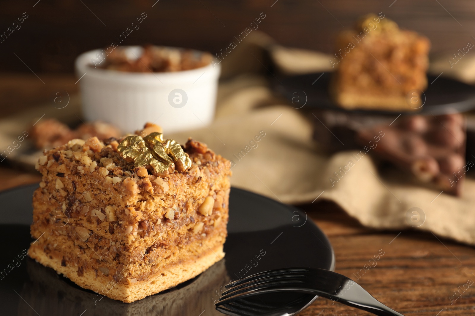 Photo of Piece of honey cake with walnuts and fork on table, closeup with space for text