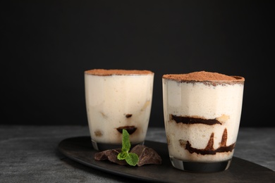 Photo of Two glasses of tiramisu cake on table against dark background, space for text