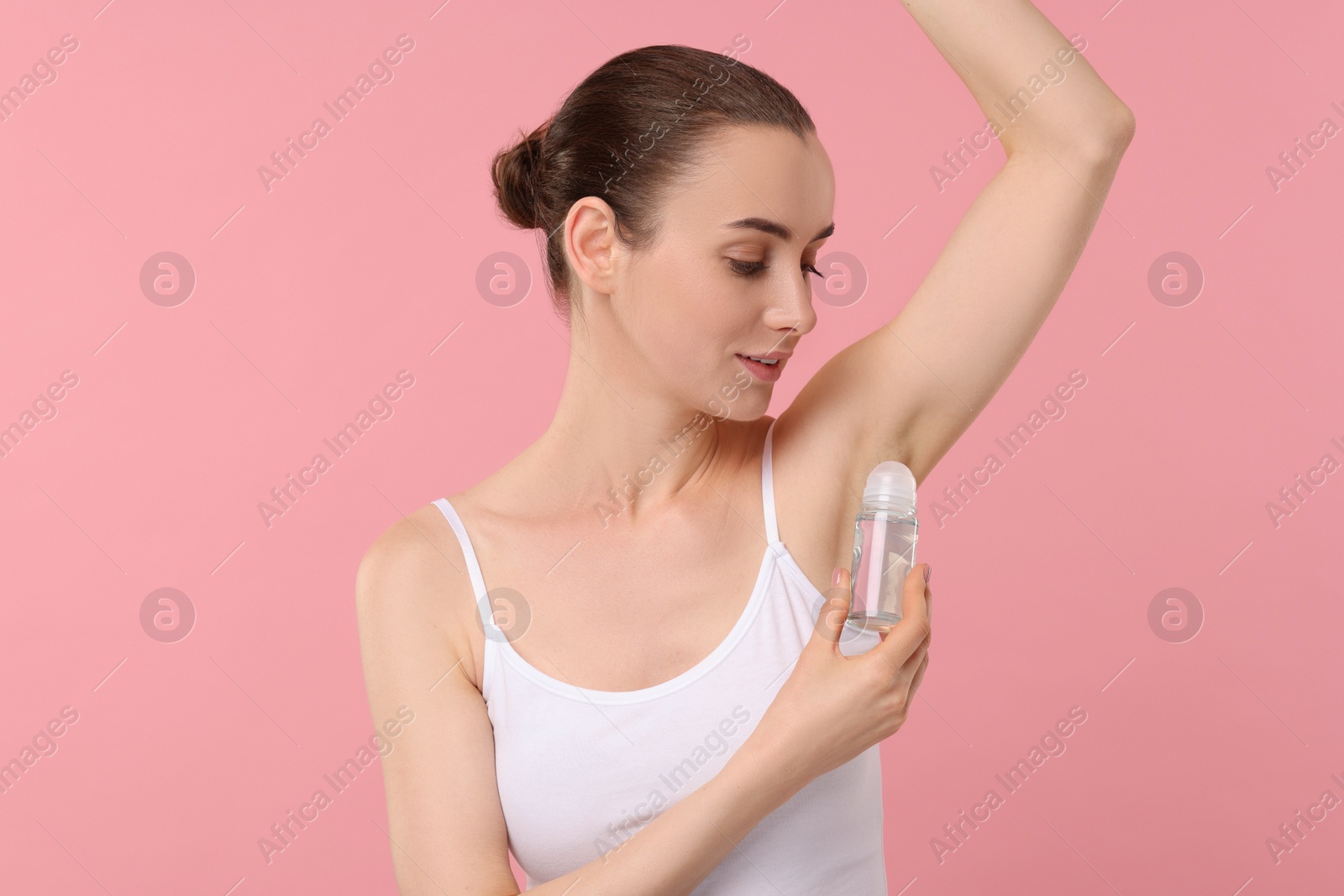 Photo of Beautiful woman applying deodorant on pink background