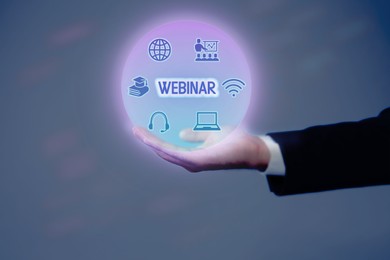 Image of Webinar. Businessman holding virtual icons on color background, closeup