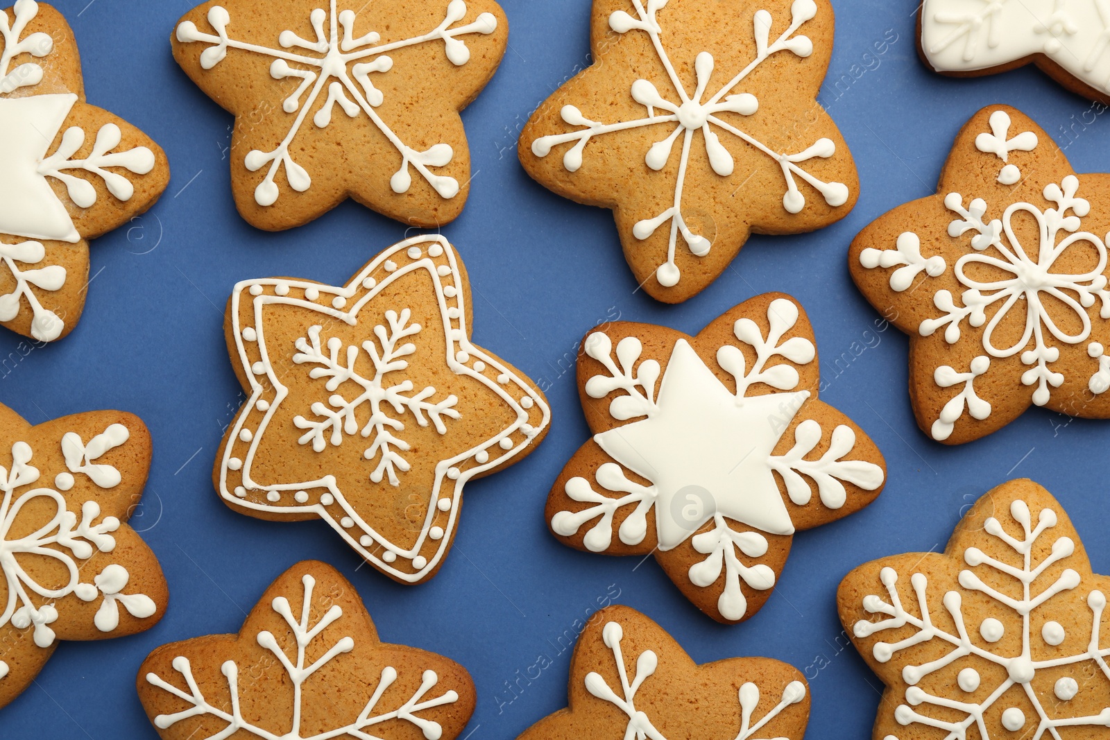 Photo of Tasty star shaped Christmas cookies with icing on blue background, flat lay