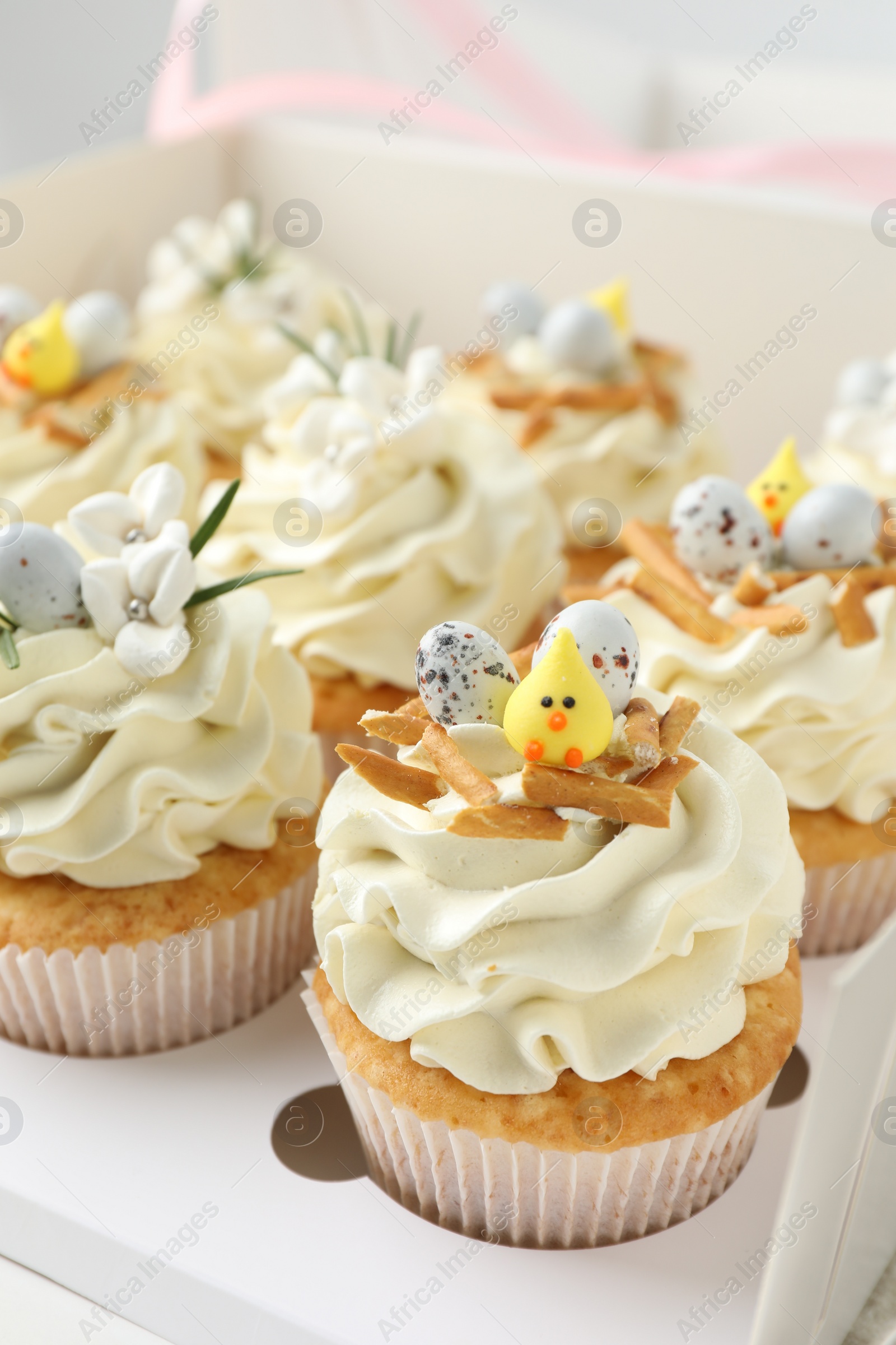 Photo of Tasty Easter cupcakes with vanilla cream in box, closeup