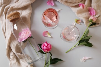 Flat lay composition with rose wine and beautiful pink peonies on white background