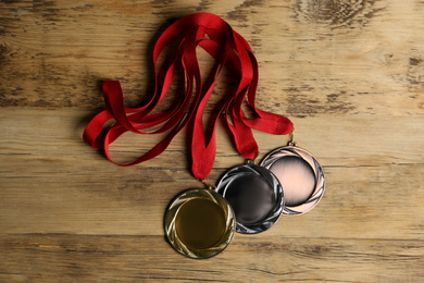 Photo of Gold, silver and bronze medals on wooden background, flat lay. Space for design