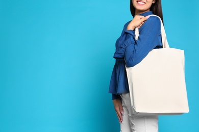 Photo of Woman with stylish blank eco bag against color background, closeup. Space for text