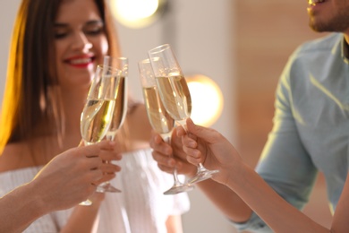 Friends clinking glasses with champagne at party indoors