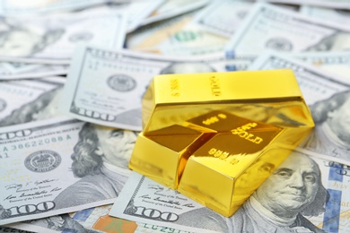 Photo of Precious shiny gold bars on dollar bills