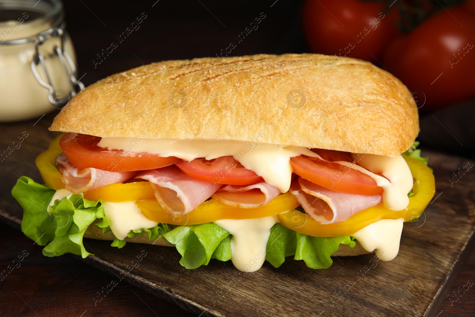 Photo of Delicious sandwich with vegetables, ham and mayonnaise on wooden table, closeup