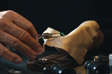 Photo of Professional jeweler working with gemstone at table, closeup