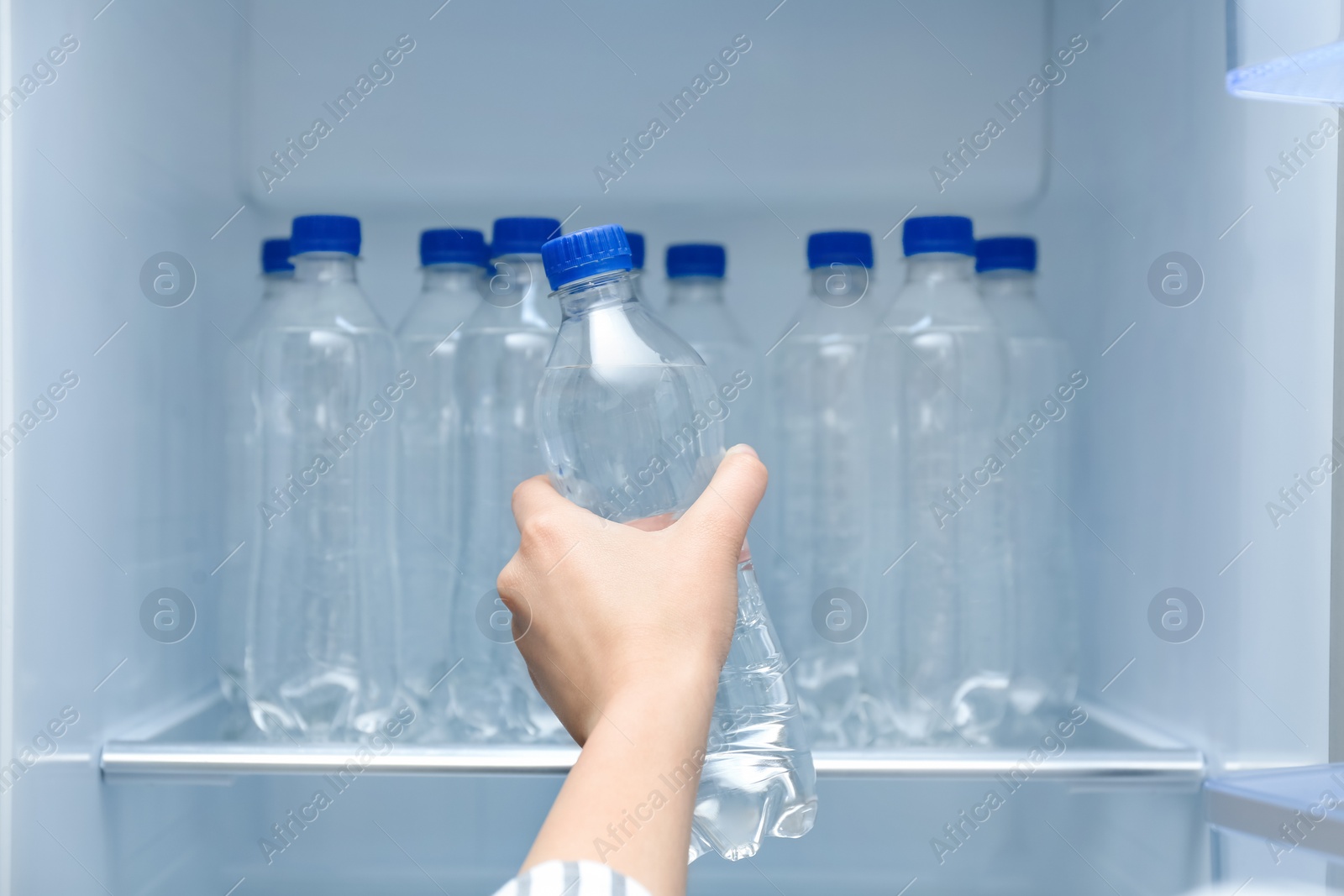 Photo of Woman taking bottle of water from refrigerator, closeup