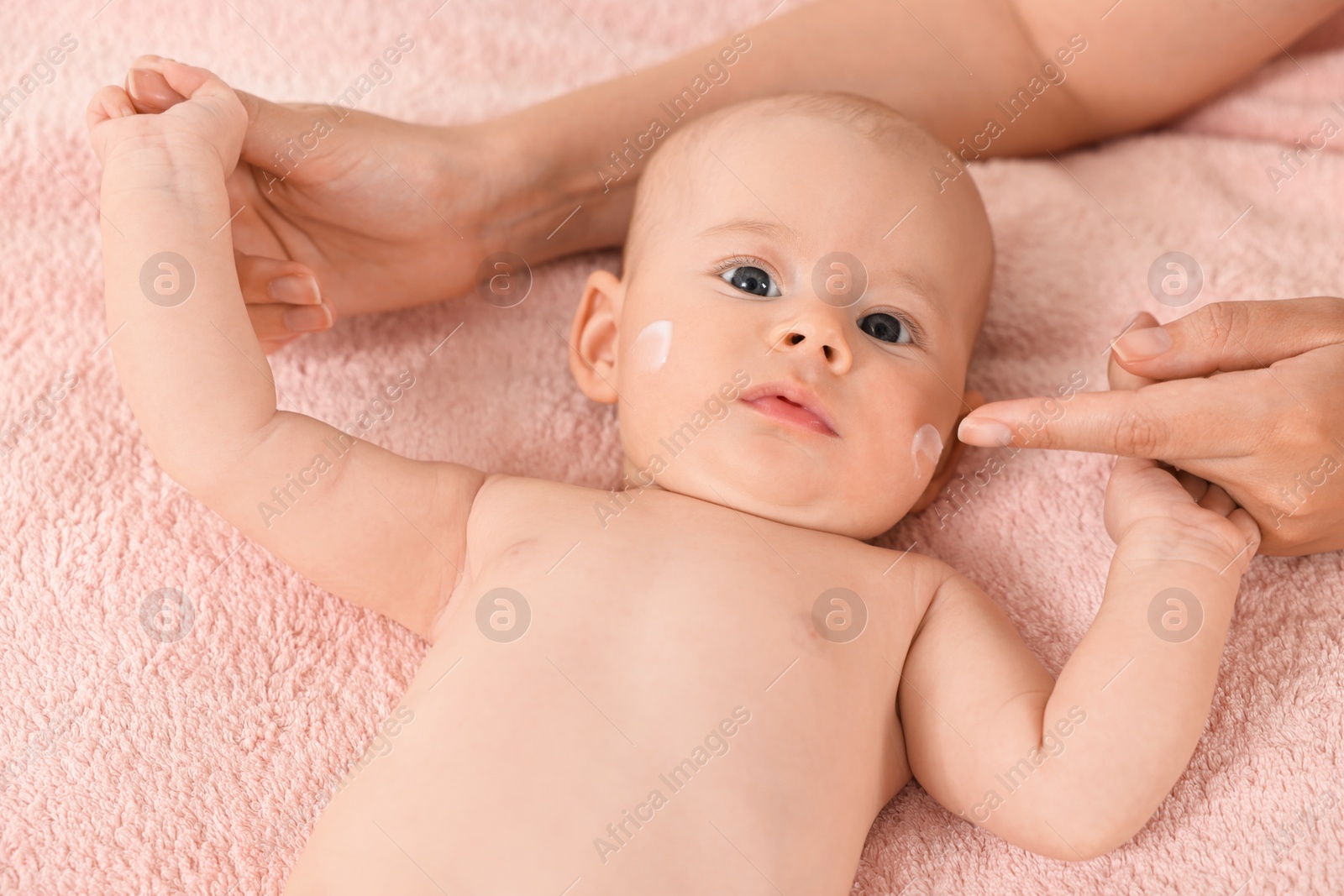 Photo of Woman applying cream onto baby`s face on bed, closeup