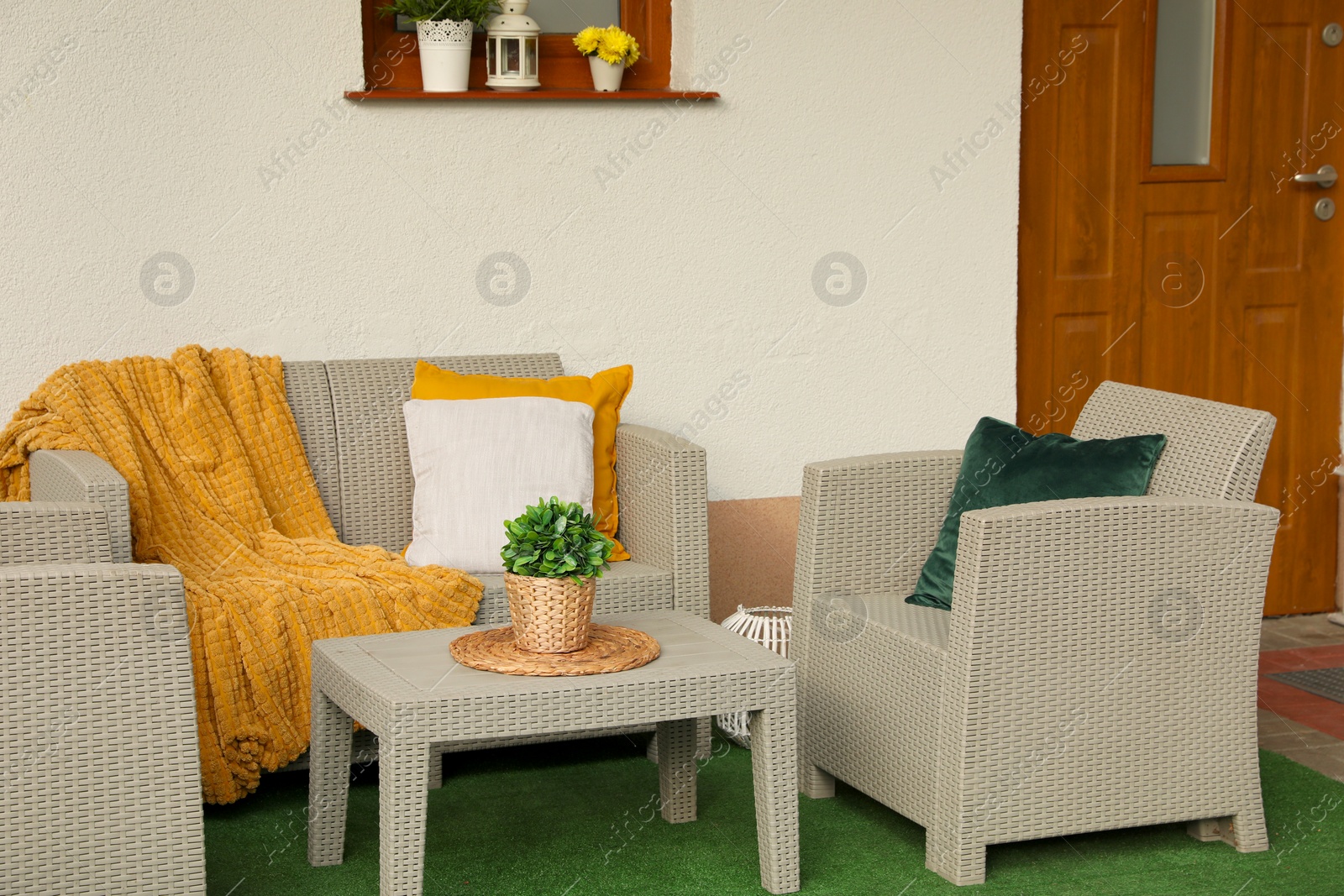 Photo of Beautiful rattan garden furniture, soft pillows, blanket and houseplant outdoors