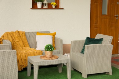 Beautiful rattan garden furniture, soft pillows, blanket and houseplant outdoors