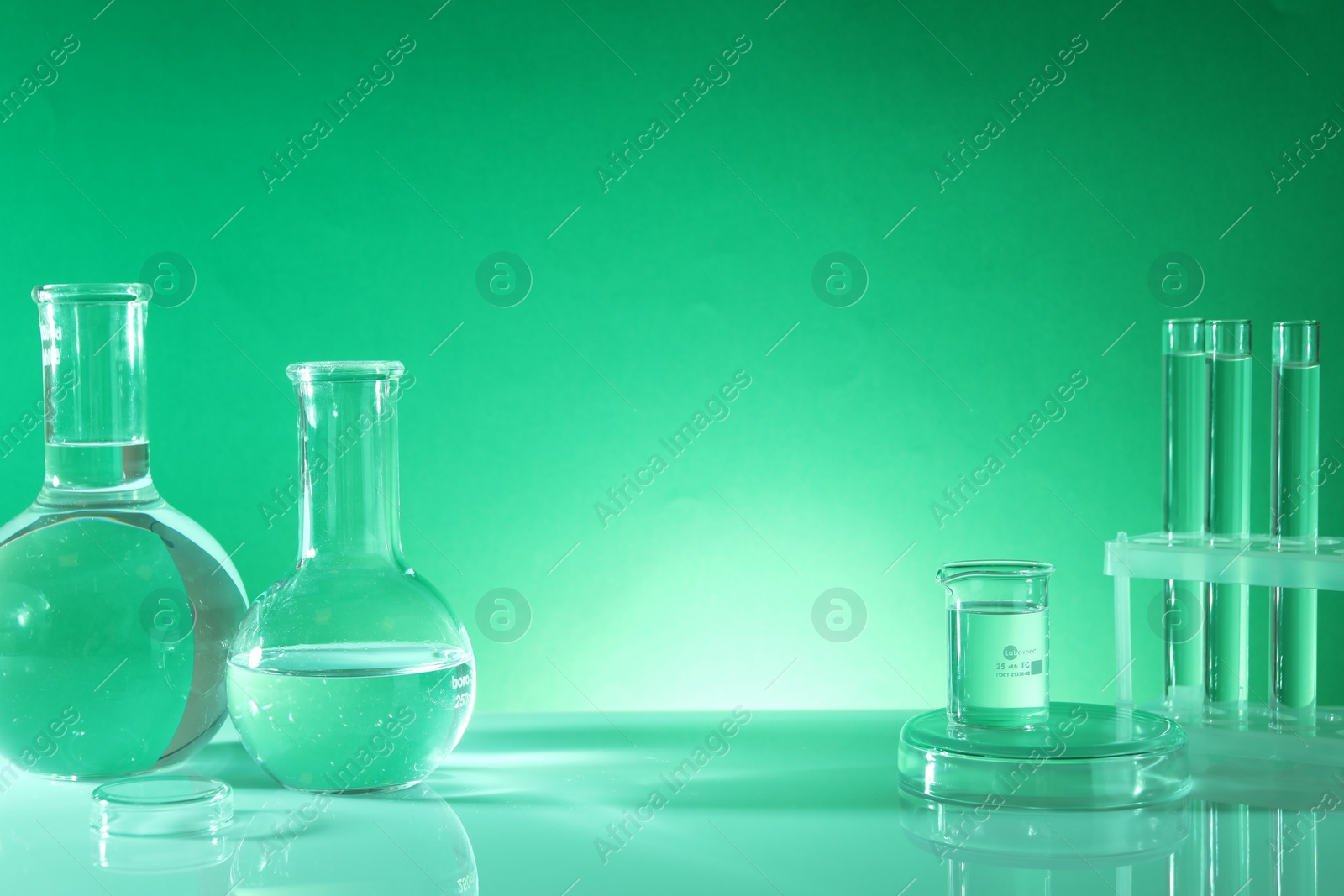 Photo of Laboratory analysis. Different glassware on table against green background