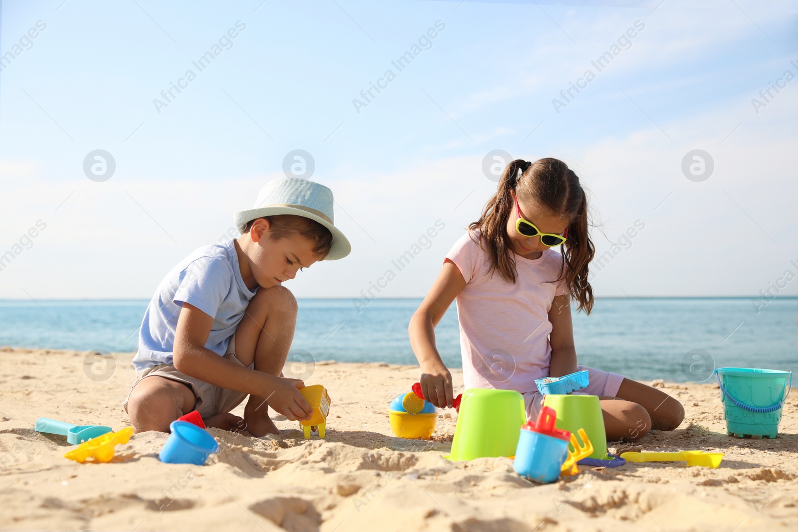 Photo of Cute little children playing with plastic toys on sandy beach