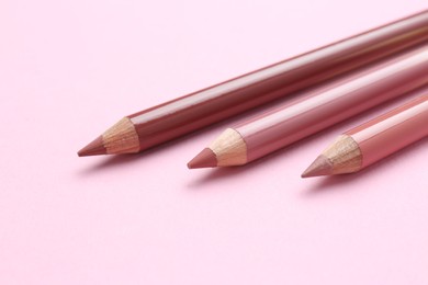 Photo of Lip pencils on pink background, closeup. Cosmetic product
