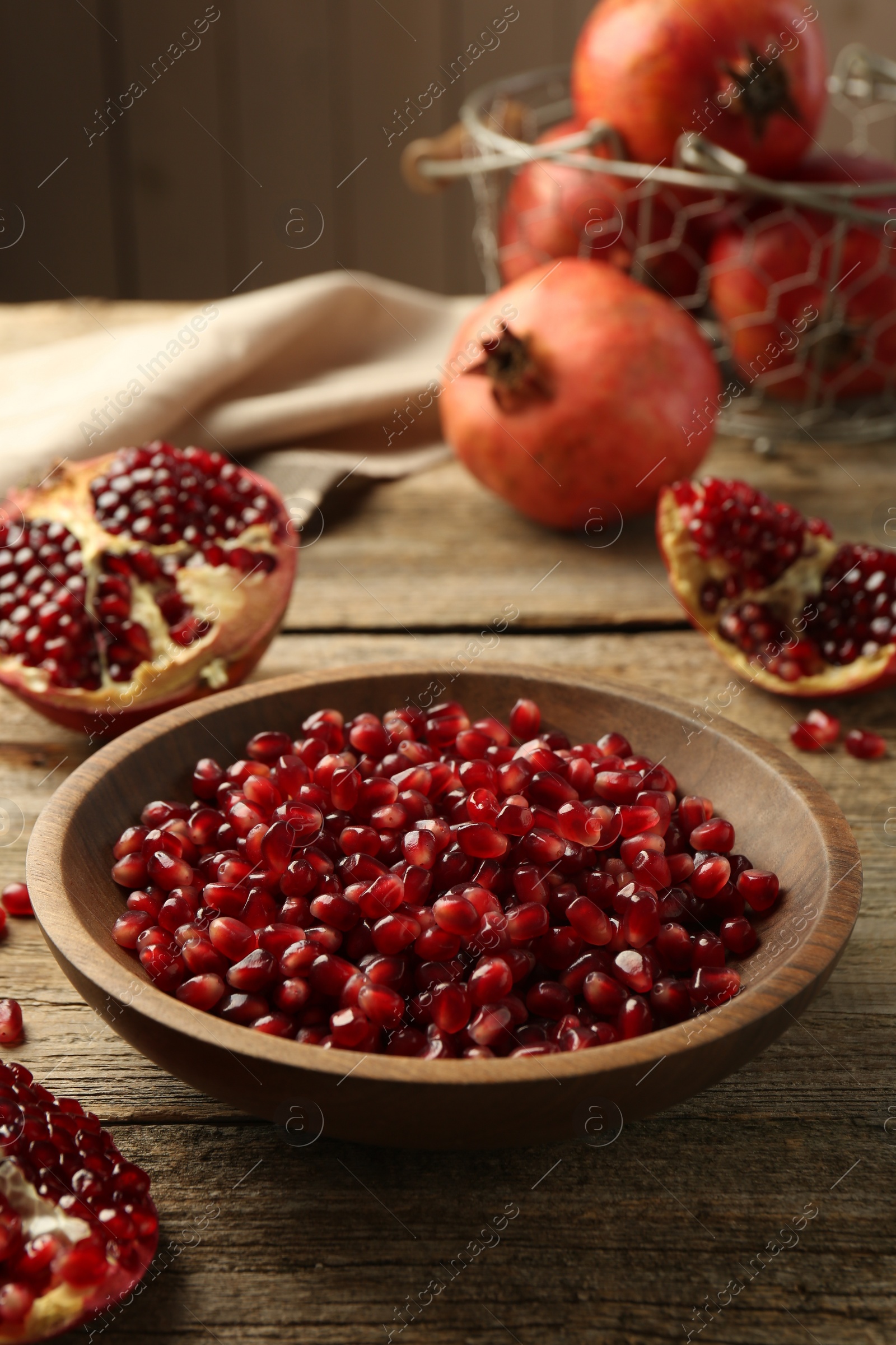 Photo of Ripe juicy pomegranate grains in bowl on wooden table