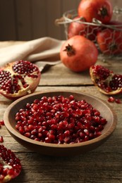 Ripe juicy pomegranate grains in bowl on wooden table