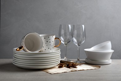 Photo of Set of clean dishware, glasses and cutlery on wooden table