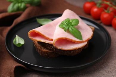 Photo of Delicious sandwich with ham on brown table, closeup