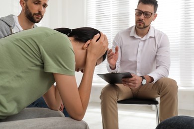 Psychotherapist working with group of drug addicted people at therapy session indoors