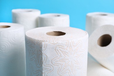 Photo of Many rolls of paper towels on light blue background, closeup