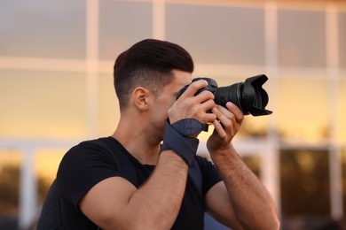 Photographer taking picture with professional camera on city street at sunset