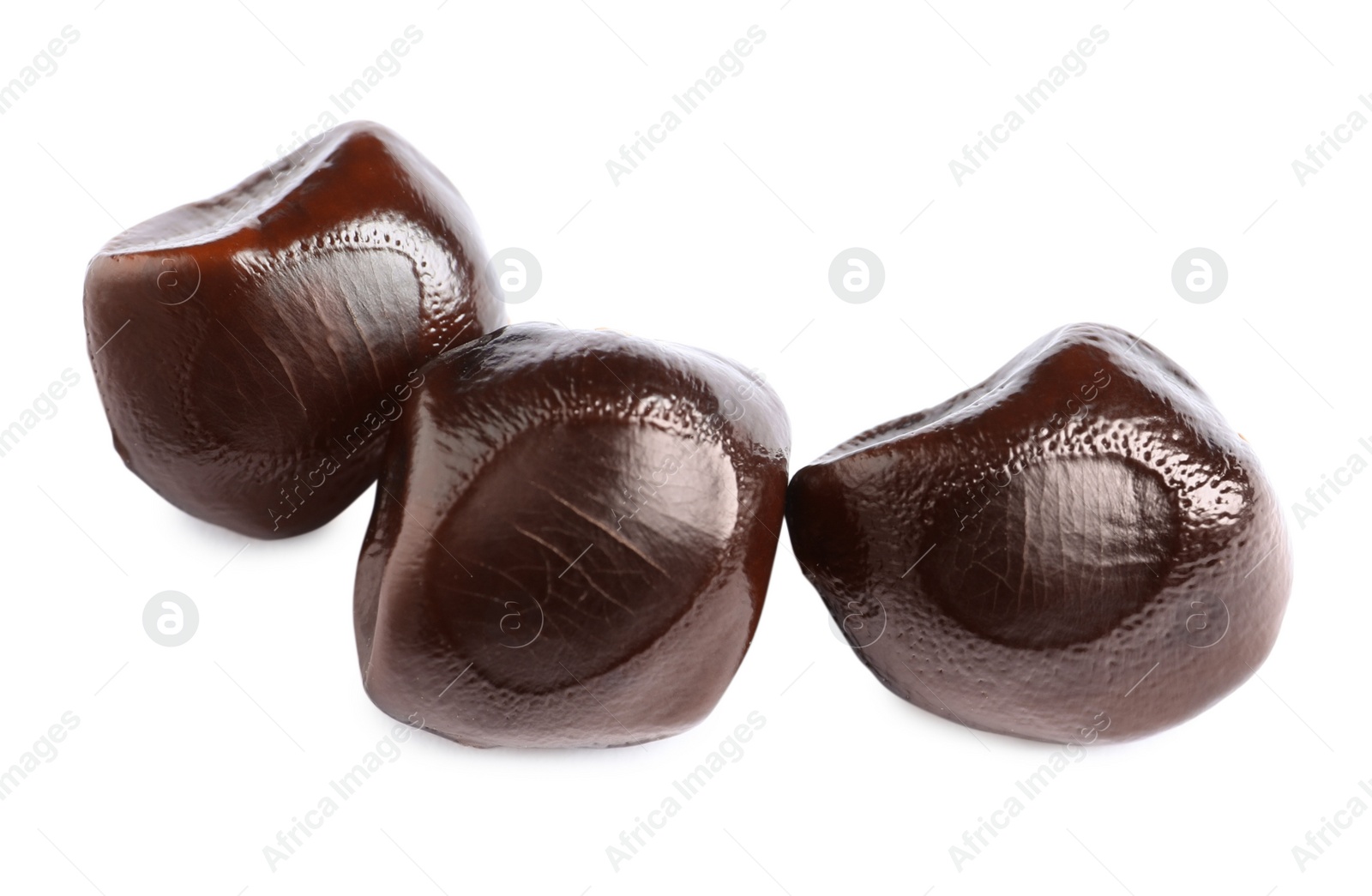 Photo of Three brown tamarind seeds on white background