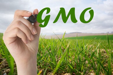 Image of GMO concept. Closeup view of woman with marker and green field