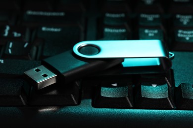 Photo of Modern usb flash drive on laptop keyboard, closeup